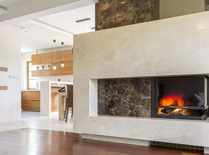 Marble fireplace in a vast living room with panelled floor, joined with bright kitchen