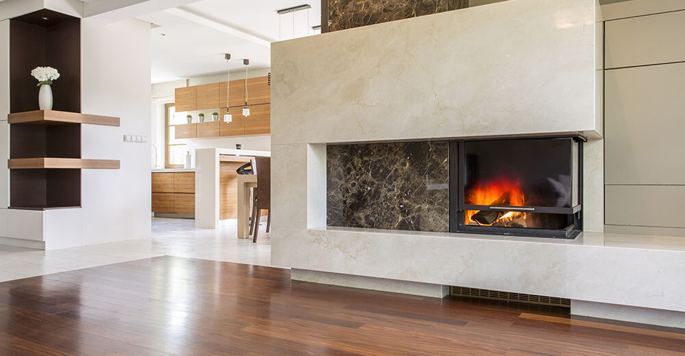 Marble fireplace in a vast living room with panelled floor, joined with bright kitchen