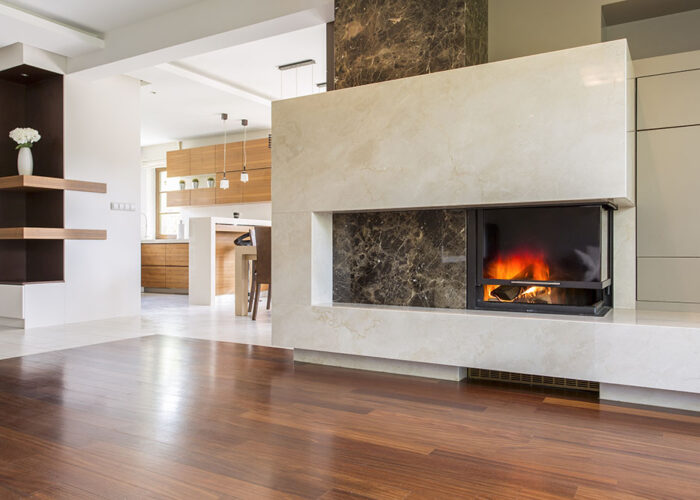 Marble fireplace in a vast living room with panelled floor, joined with bright kitchen